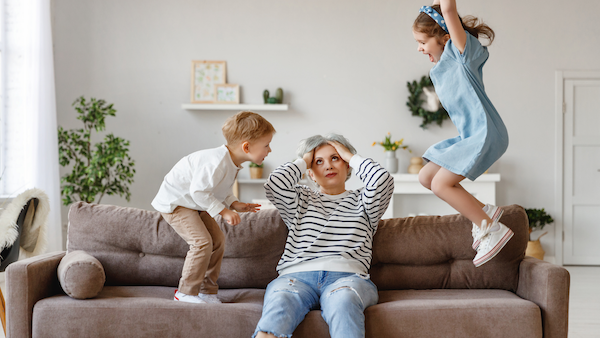 Children jumping and making noise around an irritated older woman